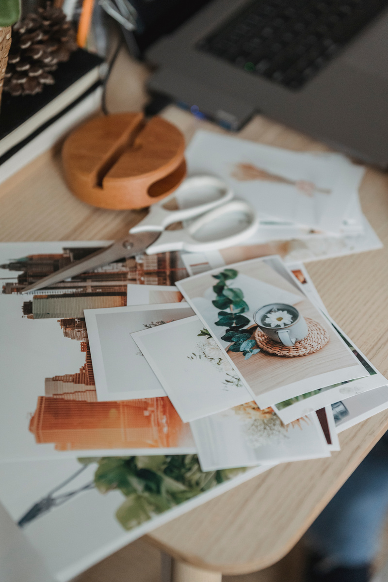 Laptop near different photos on wooden table