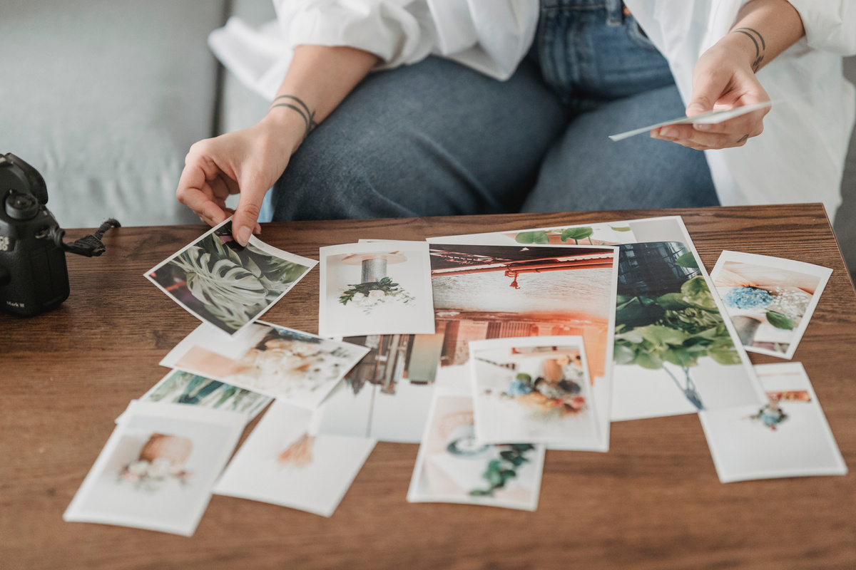 Faceless photographer picking photos at table in room