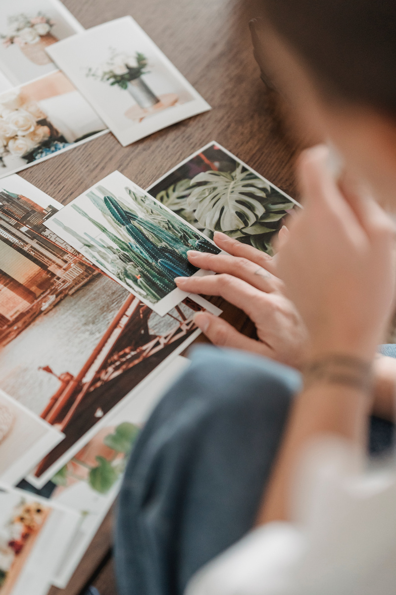 Crop person choosing photo of cactus at table